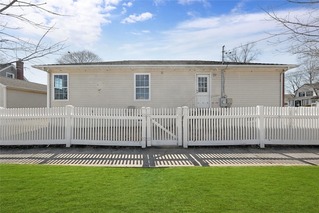 rear view of property featuring a fenced front yard and a lawn