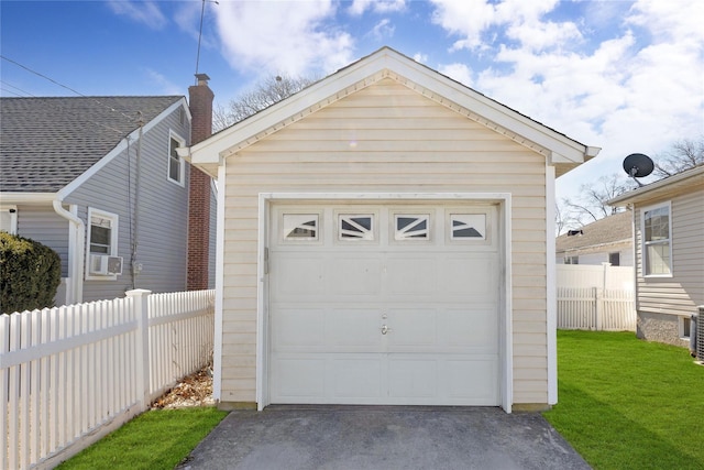 detached garage featuring aphalt driveway and fence