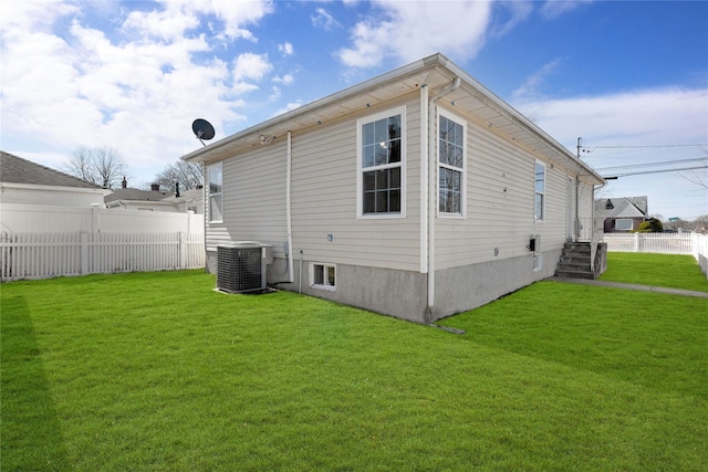 rear view of house featuring cooling unit, a yard, and fence