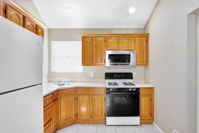 kitchen featuring a sink, stainless steel microwave, freestanding refrigerator, gas stove, and light countertops