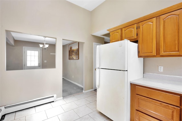 kitchen featuring freestanding refrigerator, light tile patterned flooring, light countertops, baseboard heating, and a chandelier