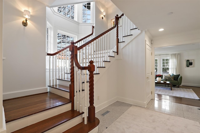 staircase with ornamental molding and tile patterned floors