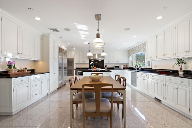 kitchen with white cabinets, appliances with stainless steel finishes, and pendant lighting