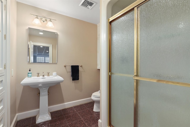 bathroom featuring sink, walk in shower, and toilet