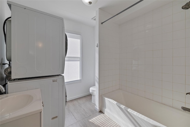 full bathroom featuring toilet, tiled shower / bath, a wealth of natural light, and stacked washer / drying machine