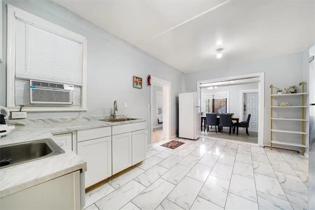 kitchen featuring white cabinetry, sink, and white fridge