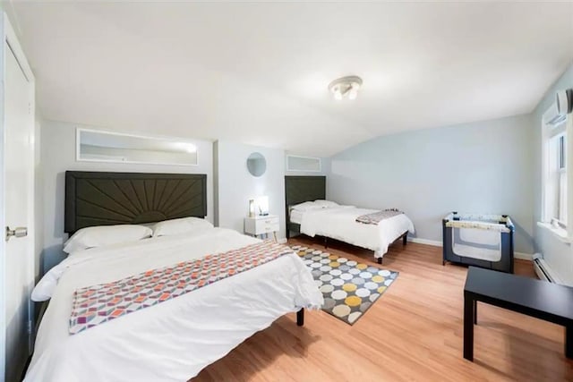 bedroom featuring hardwood / wood-style flooring, vaulted ceiling, and a baseboard radiator