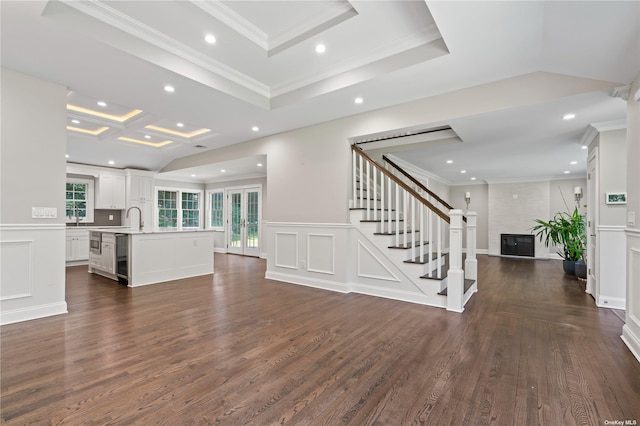 unfurnished living room with a large fireplace, sink, crown molding, and dark hardwood / wood-style floors