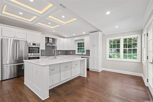 kitchen featuring white cabinetry, wall chimney exhaust hood, light stone countertops, a kitchen island with sink, and appliances with stainless steel finishes