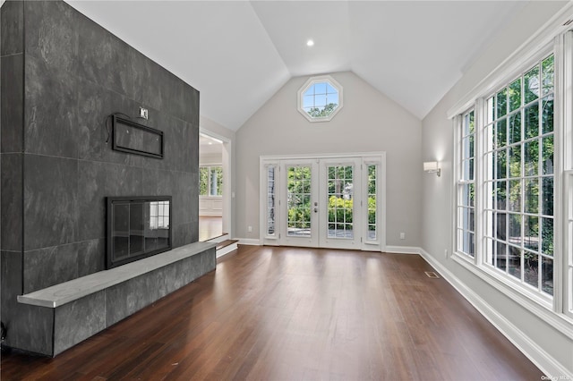 unfurnished living room featuring a high end fireplace, french doors, vaulted ceiling, and dark hardwood / wood-style flooring