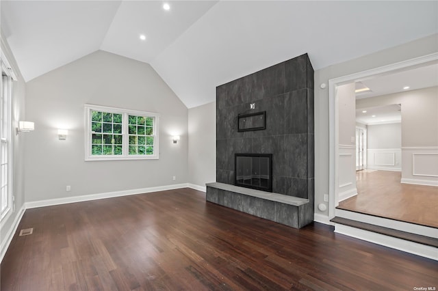 unfurnished living room featuring a tiled fireplace, vaulted ceiling, and dark hardwood / wood-style flooring