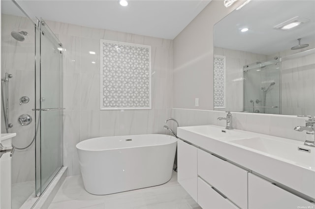 bathroom with tile walls, independent shower and bath, and vanity