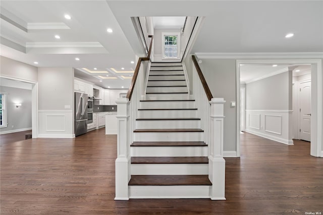 stairs with ornamental molding, hardwood / wood-style floors, and a tray ceiling