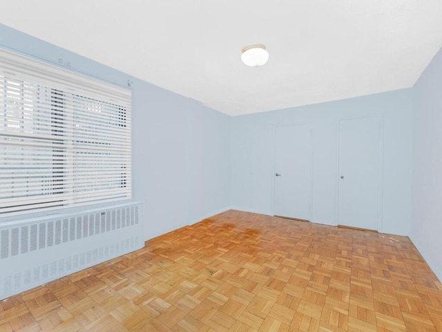 empty room with light parquet floors and radiator