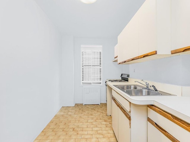 kitchen with sink, white cabinetry, and gas range oven