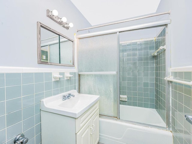 bathroom featuring tile walls, bath / shower combo with glass door, and vanity