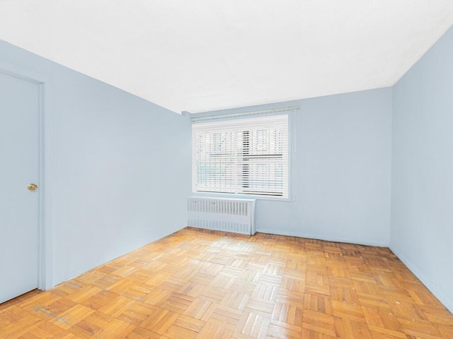 empty room with light parquet floors and radiator