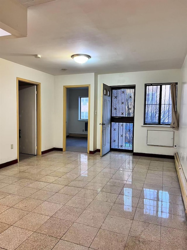 unfurnished room featuring baseboard heating and plenty of natural light