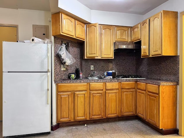 kitchen with black gas cooktop, white refrigerator, ventilation hood, and tasteful backsplash