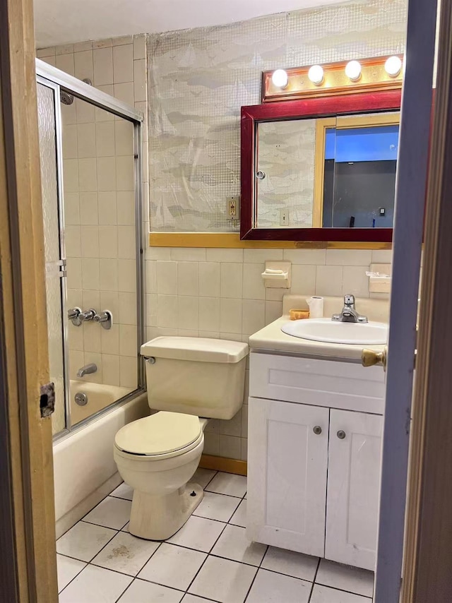 full bathroom with toilet, tile patterned flooring, tile walls, shower / bath combination with glass door, and vanity