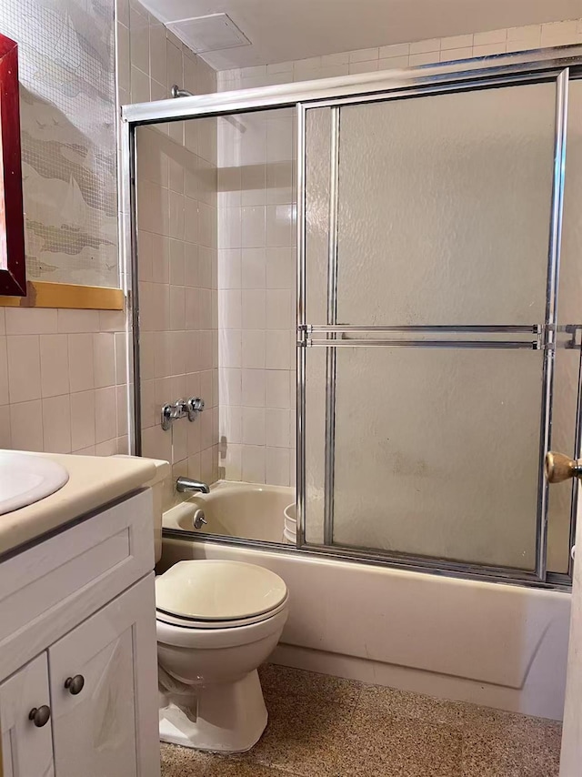 full bathroom with tile walls, enclosed tub / shower combo, vanity, and toilet