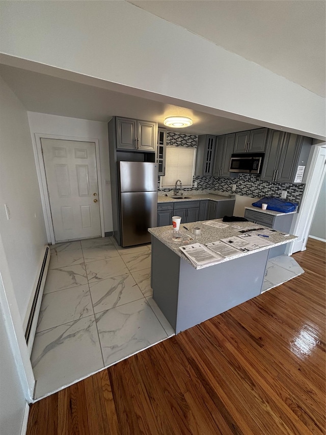 kitchen with glass insert cabinets, appliances with stainless steel finishes, marble finish floor, baseboard heating, and gray cabinets