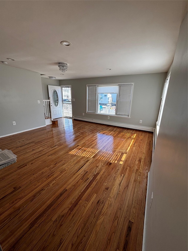 unfurnished living room with wood finished floors and baseboards