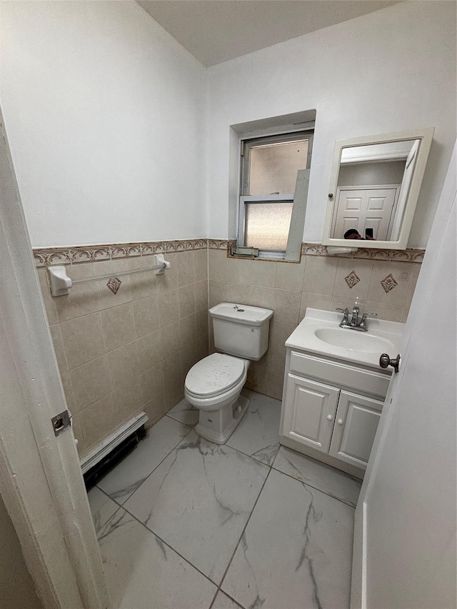 bathroom featuring toilet, marble finish floor, a wainscoted wall, and vanity