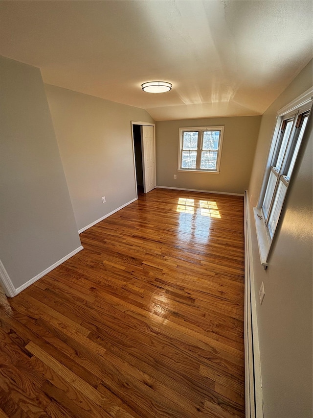 unfurnished room featuring vaulted ceiling, dark wood-type flooring, and baseboards