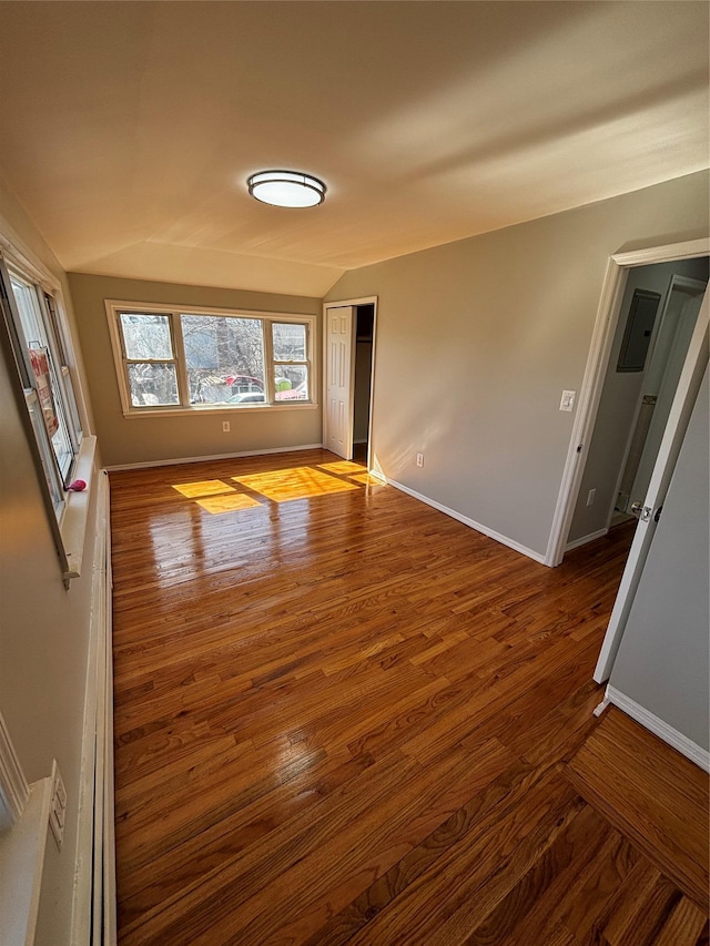 unfurnished living room with lofted ceiling, baseboards, and wood finished floors