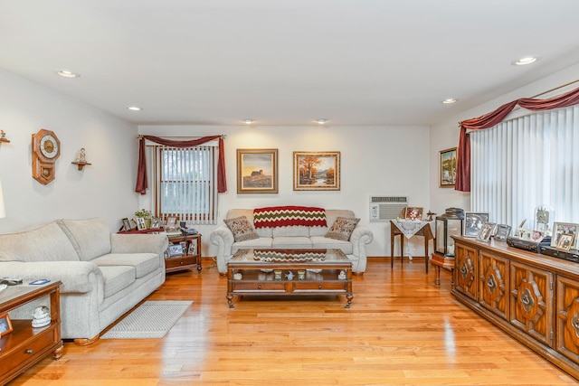 living room with an AC wall unit and light hardwood / wood-style floors