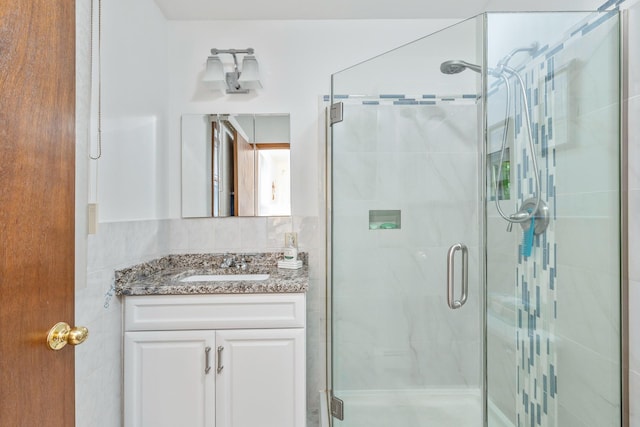 bathroom with vanity, backsplash, and a shower with door