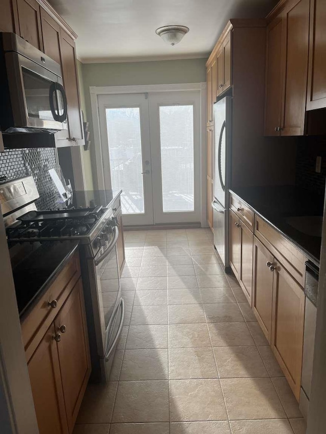 kitchen featuring light tile patterned floors, appliances with stainless steel finishes, backsplash, ornamental molding, and french doors