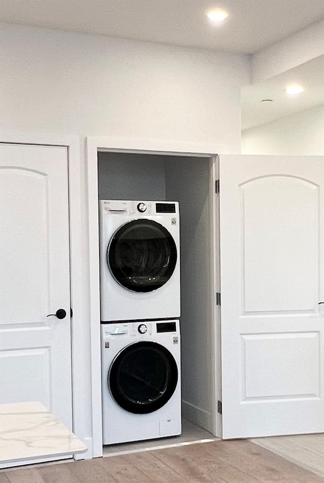 washroom with stacked washer and dryer and wood-type flooring