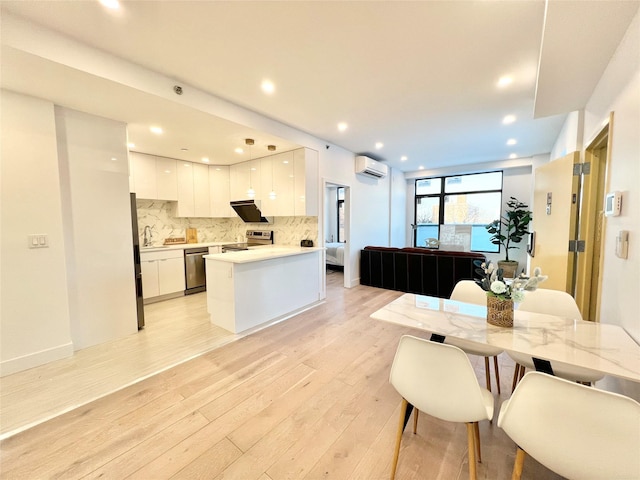 dining room featuring a wall mounted air conditioner, sink, and light wood-type flooring