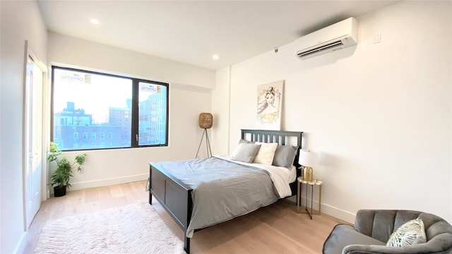 bedroom featuring a wall mounted AC and light hardwood / wood-style flooring