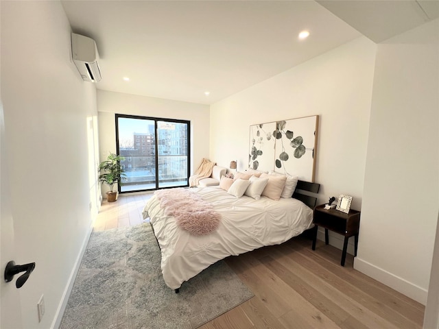 bedroom with light hardwood / wood-style floors and an AC wall unit