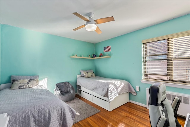 bedroom with ceiling fan, radiator heating unit, and hardwood / wood-style floors