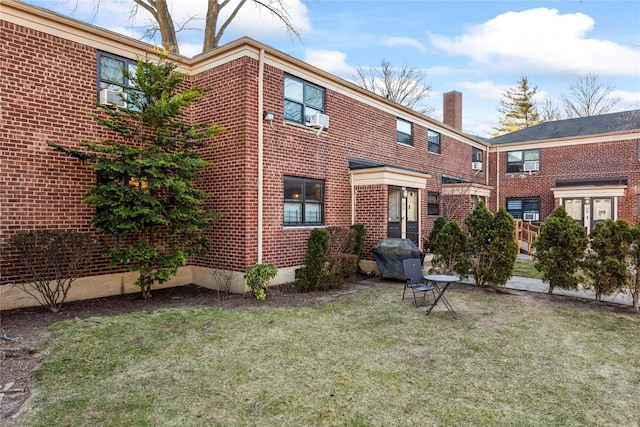 rear view of property featuring a lawn and cooling unit