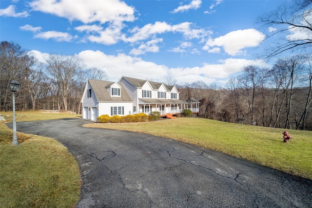 new england style home with a front yard, a garage, and a porch