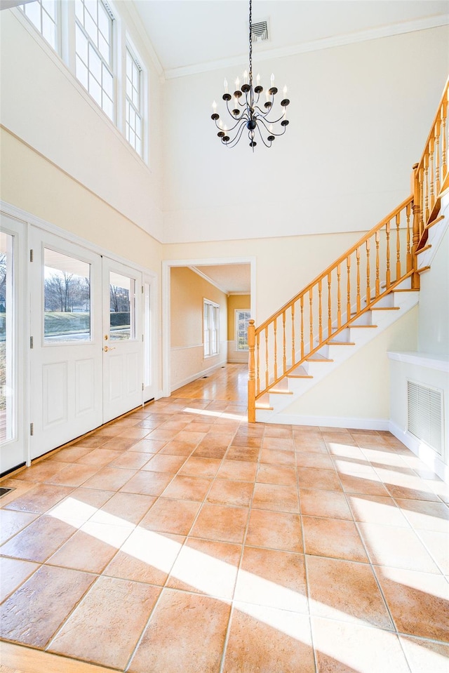 foyer featuring an inviting chandelier, light tile patterned floors, crown molding, and a high ceiling