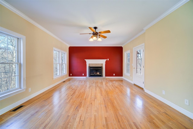 unfurnished living room featuring ceiling fan, a wealth of natural light, crown molding, and light hardwood / wood-style floors