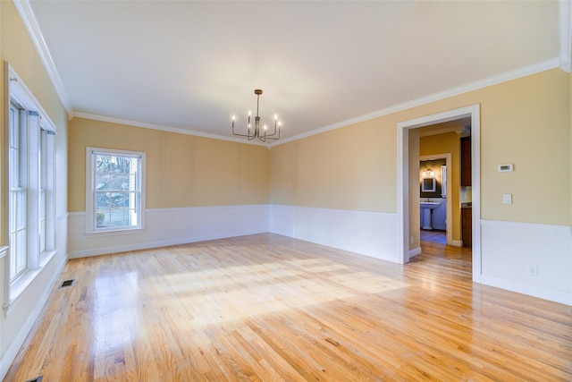 spare room featuring ornamental molding, a notable chandelier, and light wood-type flooring