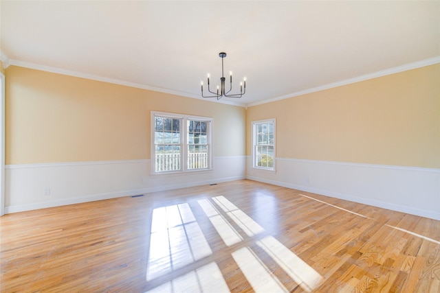 empty room with crown molding, a chandelier, and light hardwood / wood-style floors