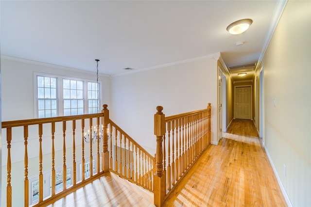 corridor with crown molding, hardwood / wood-style flooring, and a notable chandelier