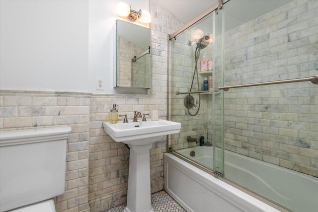 full bathroom with toilet, combined bath / shower with glass door, tile walls, tile patterned floors, and sink