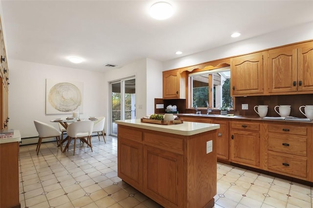 kitchen featuring baseboard heating, a center island, sink, and tasteful backsplash