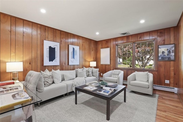 living room with a baseboard radiator, wooden walls, and light hardwood / wood-style flooring