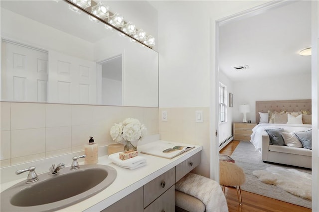 bathroom with tasteful backsplash, vanity, hardwood / wood-style floors, and a baseboard heating unit