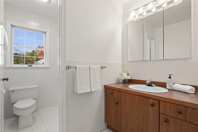 bathroom with tile walls, vanity, tile patterned flooring, and toilet